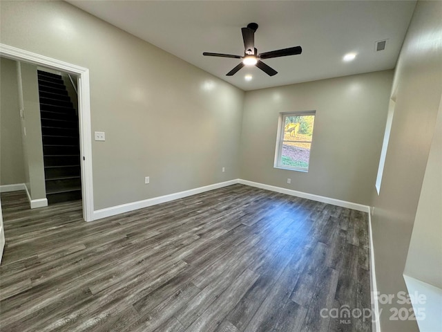 unfurnished room with ceiling fan, visible vents, baseboards, stairway, and dark wood finished floors