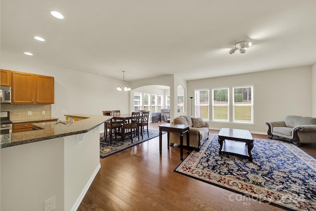 living room with sink, an inviting chandelier, and dark hardwood / wood-style flooring