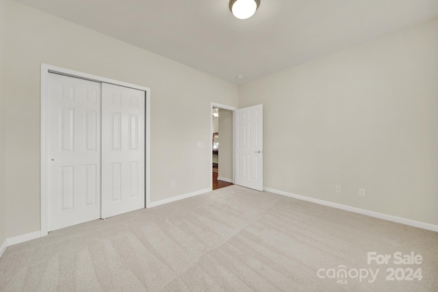 unfurnished bedroom featuring a closet and light colored carpet