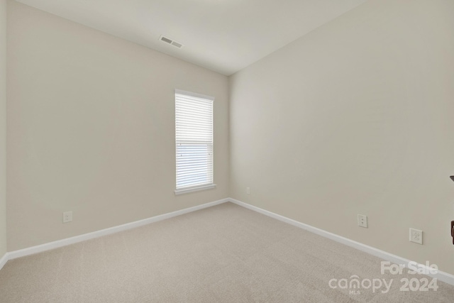 carpeted spare room with lofted ceiling