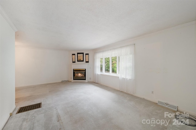 unfurnished living room with light carpet, a textured ceiling, and ornamental molding