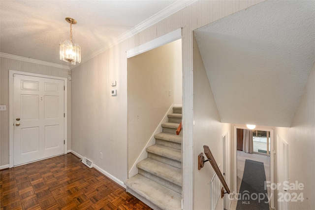 foyer entrance with a notable chandelier, dark parquet flooring, and crown molding