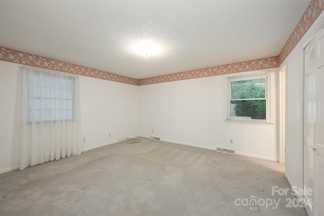 carpeted spare room featuring a textured ceiling