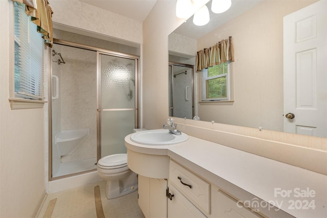 bathroom featuring vanity, a shower with shower door, and toilet