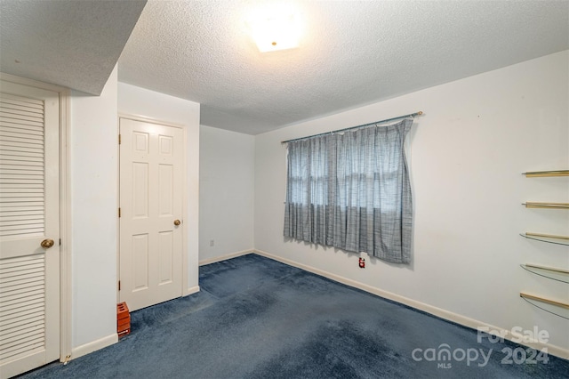 unfurnished bedroom with dark carpet and a textured ceiling