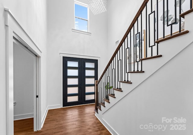 entryway featuring a notable chandelier, dark wood-type flooring, a high ceiling, and french doors