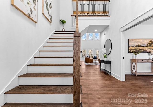 stairs featuring a high ceiling and wood-type flooring