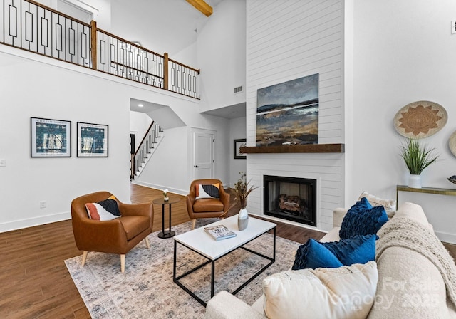 living room with a fireplace, beam ceiling, hardwood / wood-style flooring, and high vaulted ceiling