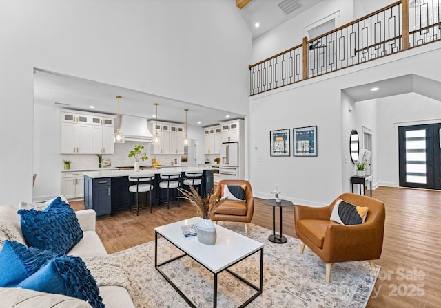 living room with light hardwood / wood-style floors and a towering ceiling