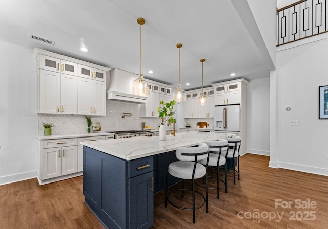 kitchen with white cabinets, pendant lighting, premium range hood, and a spacious island