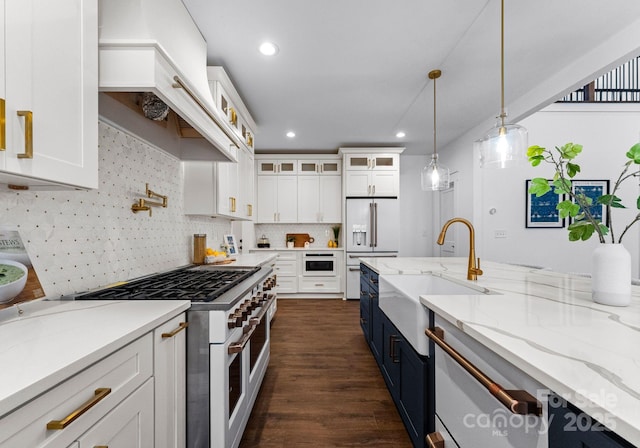 kitchen featuring pendant lighting, high end appliances, and white cabinetry