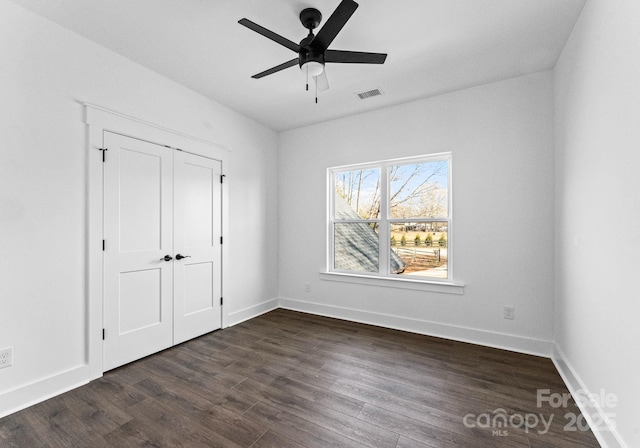 unfurnished bedroom featuring dark hardwood / wood-style flooring, ceiling fan, and a closet