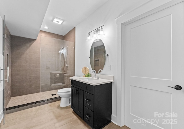 bathroom featuring a tile shower, tile patterned floors, vanity, and toilet