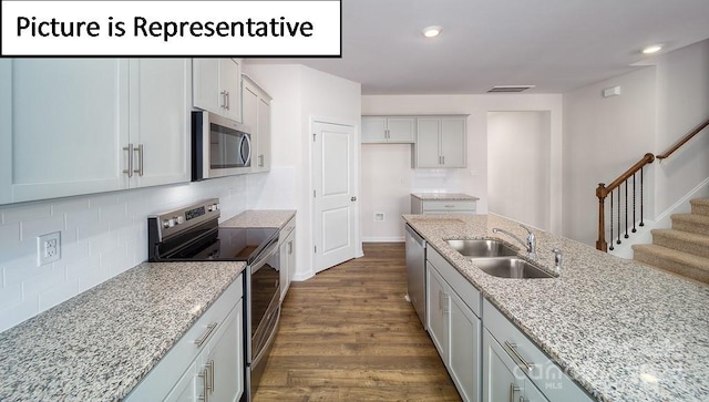 kitchen featuring light stone counters, sink, tasteful backsplash, dark wood-type flooring, and stainless steel appliances