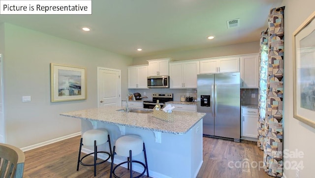 kitchen with a kitchen island with sink, appliances with stainless steel finishes, tasteful backsplash, and white cabinetry