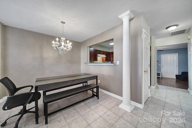 dining room with a notable chandelier, a textured ceiling, light tile patterned floors, and decorative columns