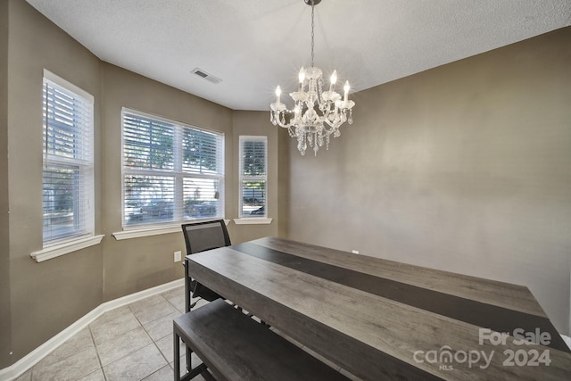 dining space featuring a notable chandelier, a textured ceiling, and light tile patterned floors