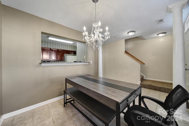 tiled dining room with a textured ceiling, a chandelier, and decorative columns