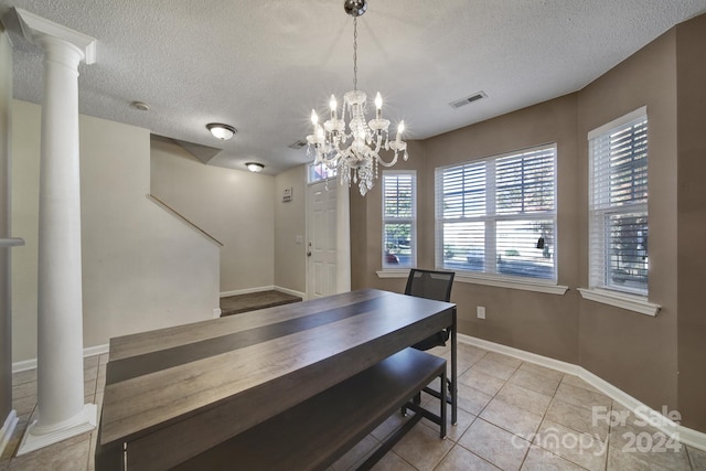 dining space featuring decorative columns, light tile patterned flooring, a textured ceiling, and an inviting chandelier