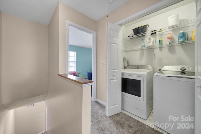 laundry room featuring light carpet, a textured ceiling, and separate washer and dryer