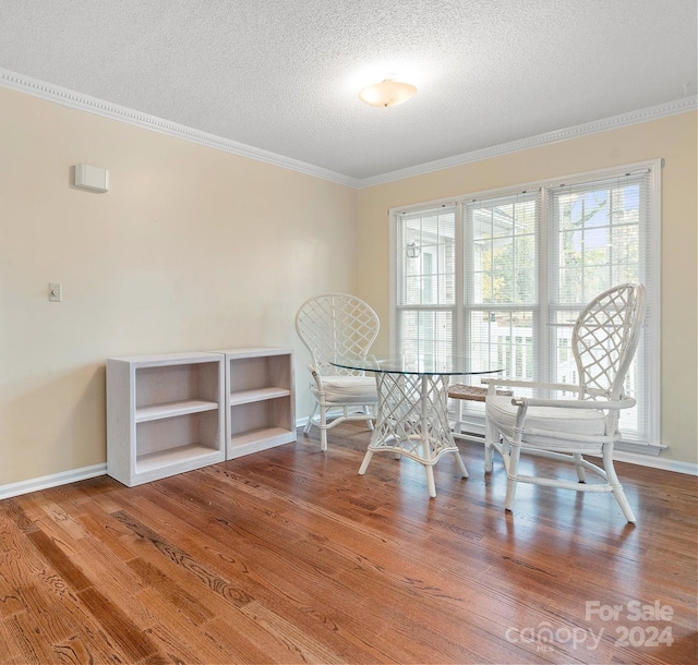 unfurnished dining area featuring a textured ceiling, ornamental molding, and hardwood / wood-style flooring