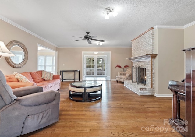 living room featuring a fireplace, crown molding, light hardwood / wood-style floors, and plenty of natural light