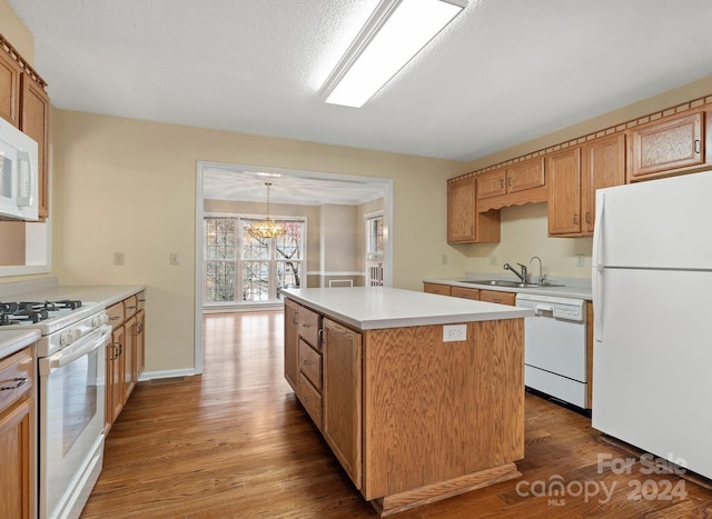 kitchen with pendant lighting, white appliances, hardwood / wood-style floors, and a center island