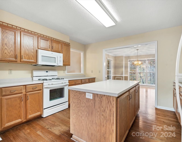 kitchen with light hardwood / wood-style floors, a textured ceiling, white appliances, a kitchen island, and pendant lighting