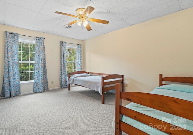 carpeted bedroom with a drop ceiling and ceiling fan