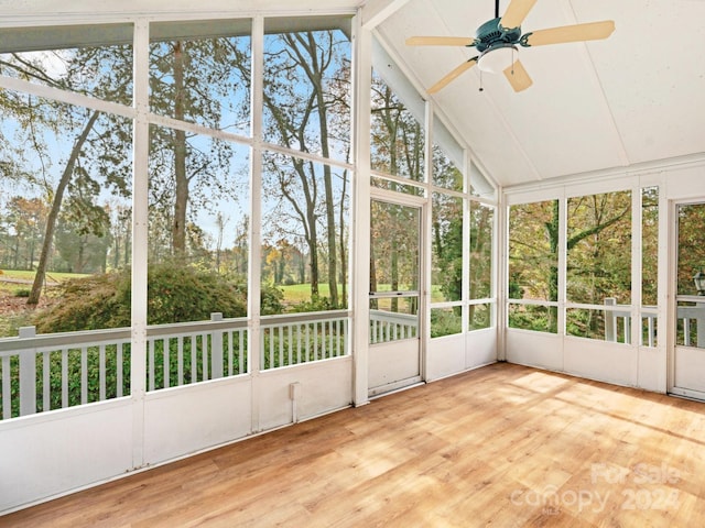 unfurnished sunroom featuring a wealth of natural light, ceiling fan, and vaulted ceiling with beams