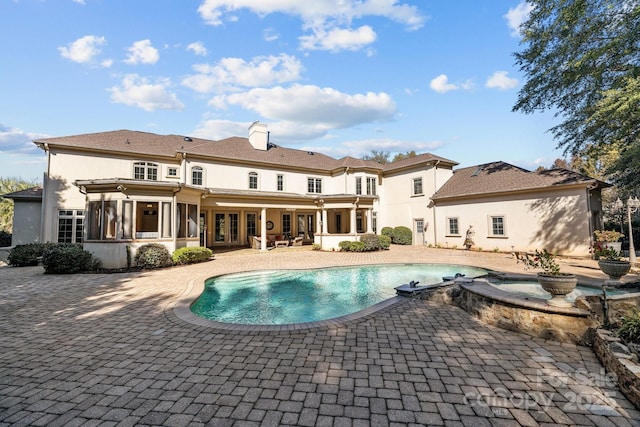 view of pool with a pool with connected hot tub, a patio area, and a sunroom