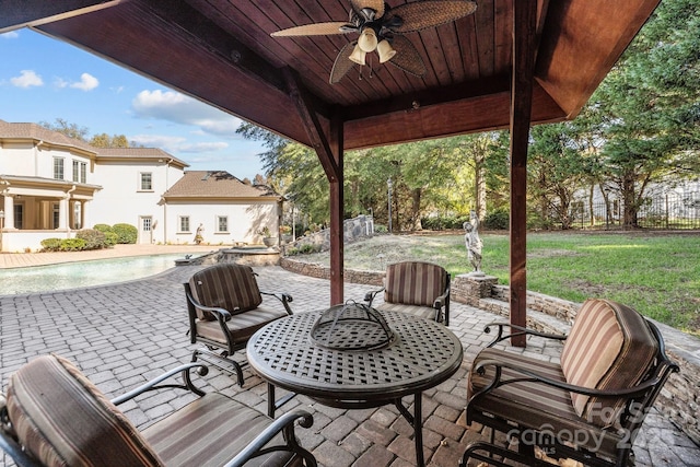 view of patio / terrace with a ceiling fan, an outdoor pool, and fence