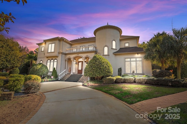 mediterranean / spanish-style house featuring a balcony, driveway, and stucco siding