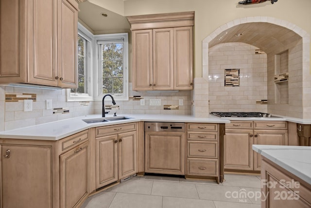 kitchen featuring a sink, light countertops, light brown cabinets, stainless steel gas cooktop, and backsplash