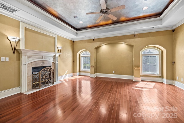 unfurnished living room with visible vents, a tray ceiling, crown molding, and a tile fireplace