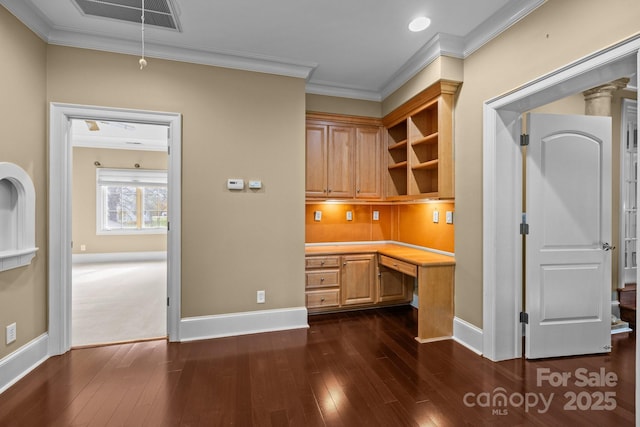 unfurnished office featuring attic access, visible vents, ornamental molding, and built in desk