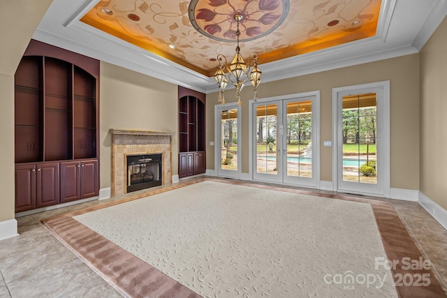 unfurnished living room with ornamental molding, a tray ceiling, a fireplace, and plenty of natural light