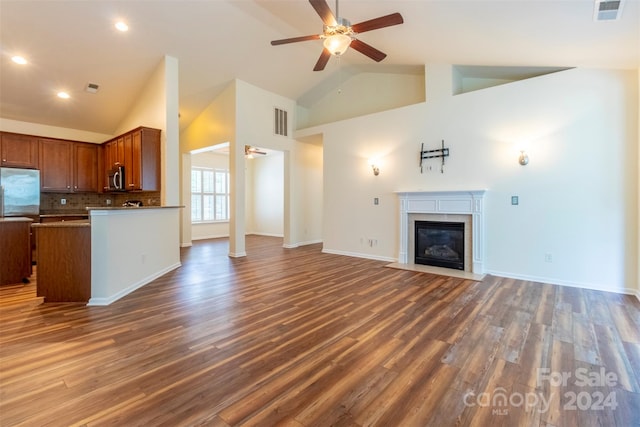 unfurnished living room featuring high vaulted ceiling, ceiling fan, and dark wood-type flooring