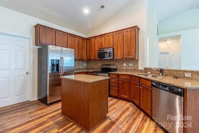 kitchen featuring lofted ceiling, sink, stainless steel appliances, light stone countertops, and light hardwood / wood-style floors