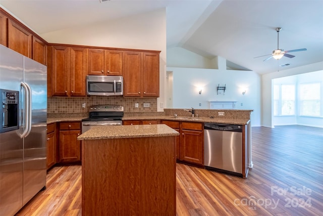 kitchen featuring ceiling fan, lofted ceiling, light hardwood / wood-style flooring, stainless steel appliances, and a center island