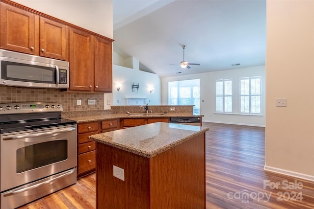 kitchen featuring lofted ceiling, light wood-type flooring, decorative backsplash, a center island, and stainless steel appliances