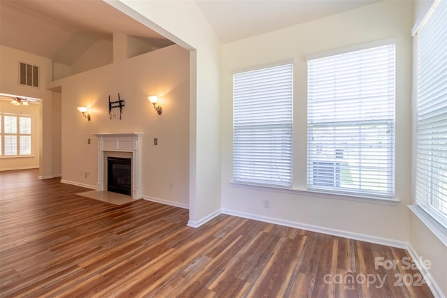 unfurnished living room featuring lofted ceiling, plenty of natural light, and dark wood-type flooring