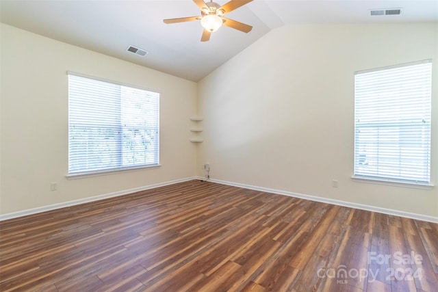 unfurnished room featuring dark wood-type flooring, vaulted ceiling, and a wealth of natural light