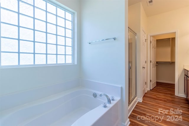 bathroom with vanity, plus walk in shower, hardwood / wood-style flooring, and a wealth of natural light