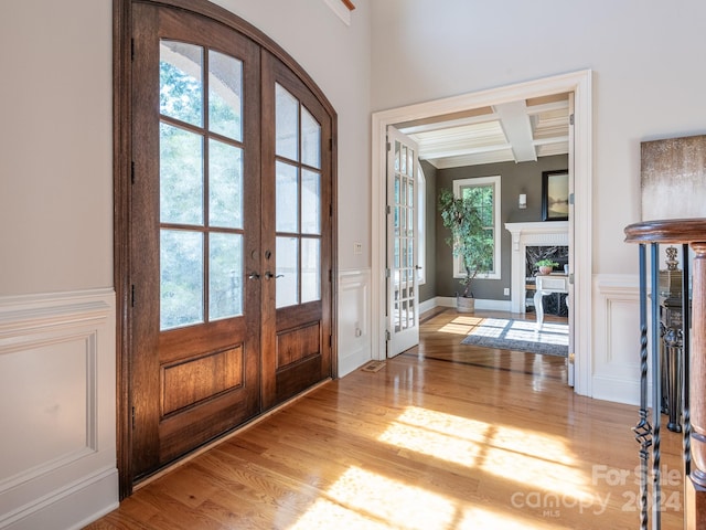 entrance foyer featuring light hardwood / wood-style floors, french doors, beamed ceiling, and coffered ceiling