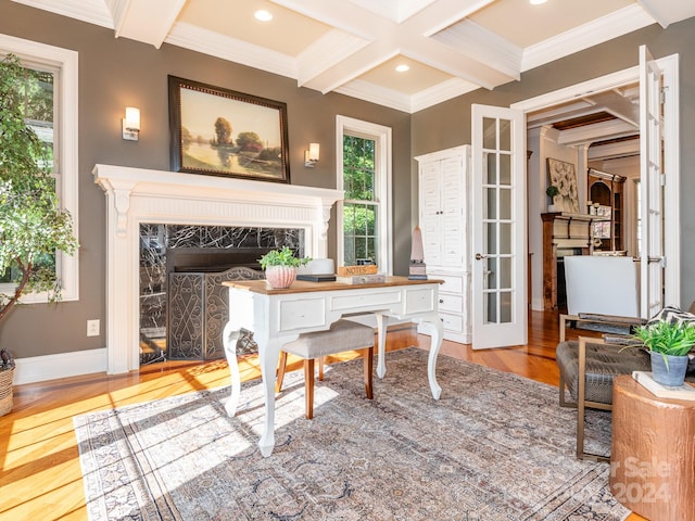 office space with coffered ceiling, beam ceiling, light hardwood / wood-style flooring, ornamental molding, and a fireplace