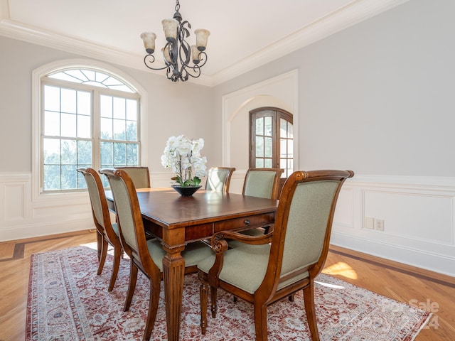 dining space with crown molding, light hardwood / wood-style flooring, an inviting chandelier, and plenty of natural light