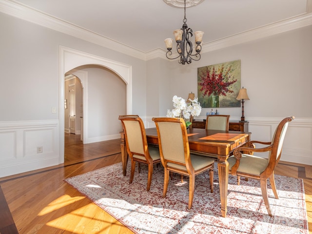 dining room featuring crown molding, hardwood / wood-style flooring, and a notable chandelier