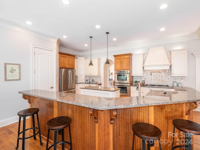 kitchen featuring a large island with sink, tasteful backsplash, appliances with stainless steel finishes, and a breakfast bar area