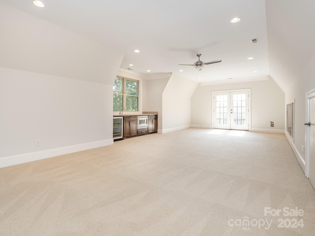 additional living space featuring light carpet, plenty of natural light, and beverage cooler